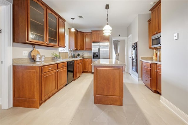 kitchen featuring sink, stainless steel appliances, light tile patterned floors, pendant lighting, and a kitchen island