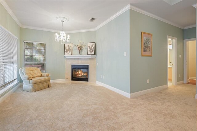 sitting room with a chandelier, carpet floors, crown molding, and a tiled fireplace