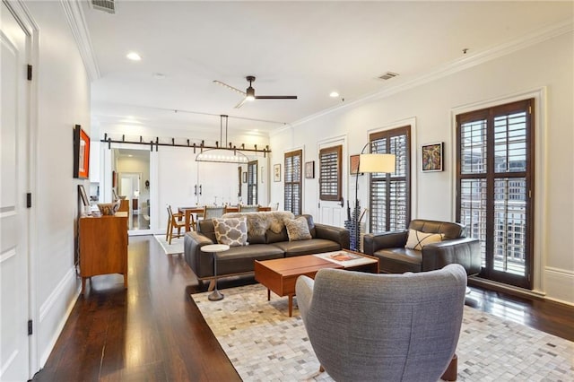 living room with hardwood / wood-style flooring, ceiling fan, a barn door, and crown molding