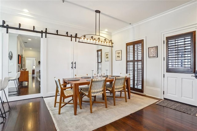 dining area with hardwood / wood-style floors, a barn door, and ornamental molding