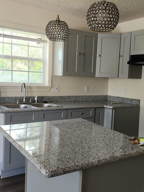 kitchen featuring light stone countertops, sink, dark hardwood / wood-style floors, a textured ceiling, and gray cabinets