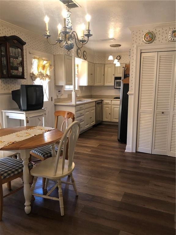 dining space featuring wallpapered walls, a wainscoted wall, ornamental molding, dark wood-type flooring, and a notable chandelier