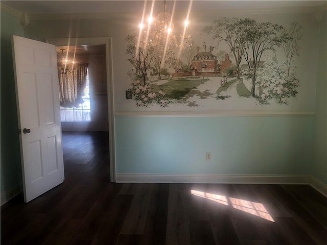 empty room with a chandelier, dark wood-type flooring, crown molding, and baseboards