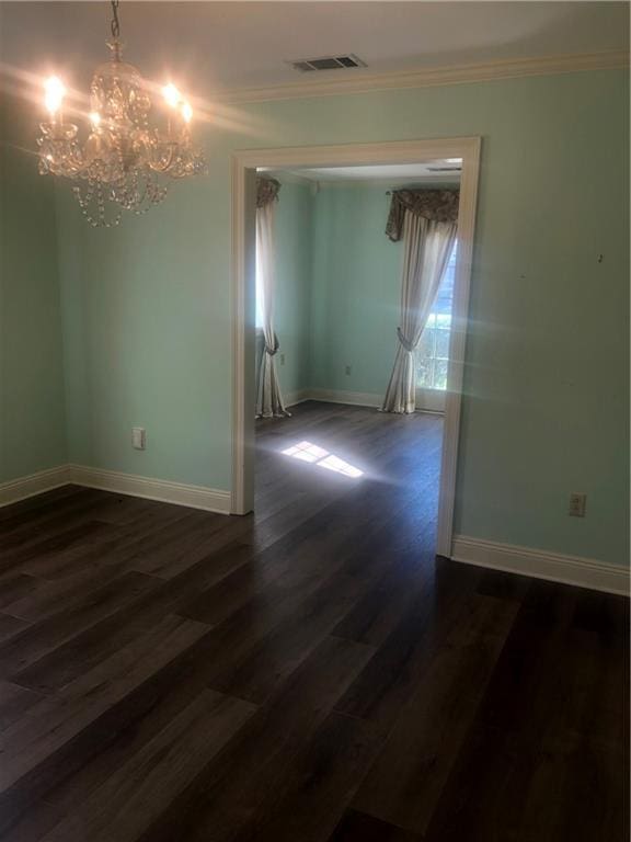 empty room with dark wood-style flooring, visible vents, ornamental molding, a chandelier, and baseboards