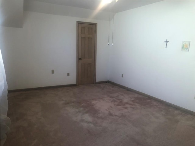 unfurnished room with dark colored carpet and baseboards