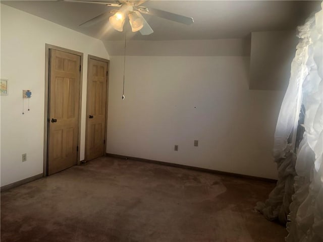 unfurnished bedroom with dark colored carpet, ceiling fan, and baseboards