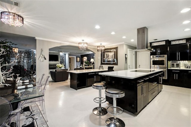 kitchen with a breakfast bar, a kitchen island, extractor fan, and decorative light fixtures