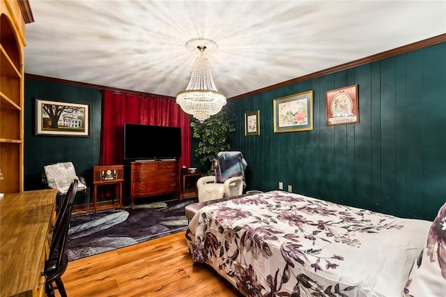 bedroom with hardwood / wood-style floors, an inviting chandelier, ornamental molding, and wood walls