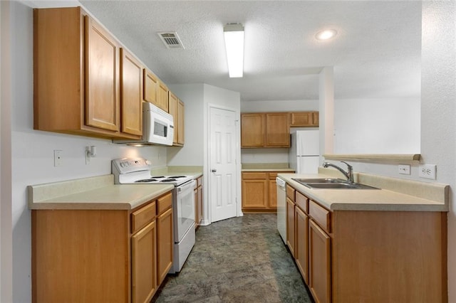 kitchen with a textured ceiling, sink, and white appliances