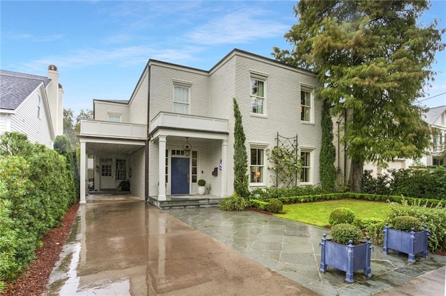 view of front facade with a balcony, a front yard, and a carport