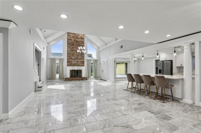 kitchen with stainless steel fridge, decorative light fixtures, high vaulted ceiling, white cabinets, and a breakfast bar area