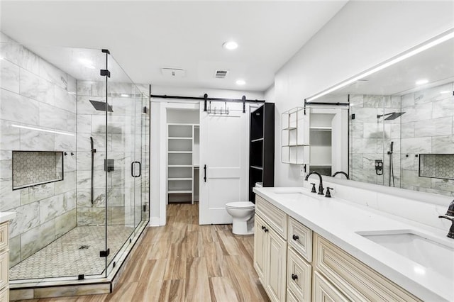 bathroom featuring hardwood / wood-style floors, vanity, toilet, and a shower with door