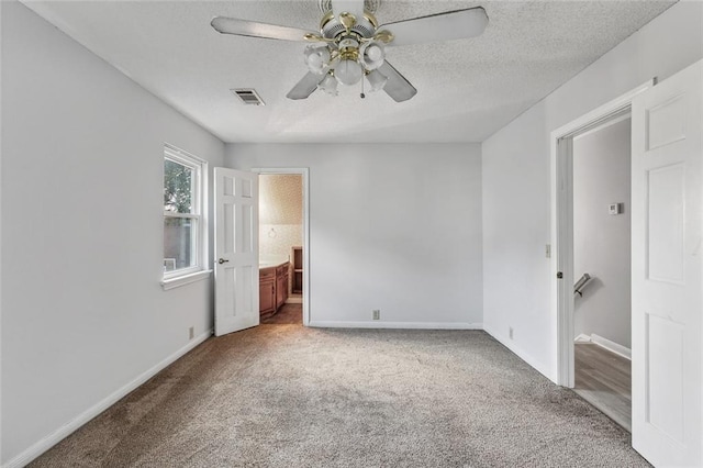 unfurnished bedroom featuring ceiling fan, carpet, ensuite bathroom, and a textured ceiling