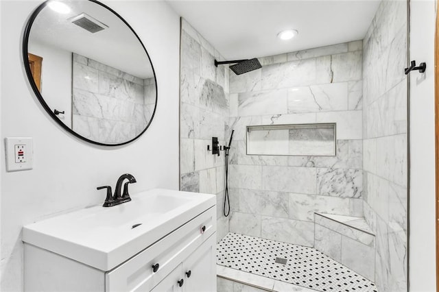 bathroom featuring a tile shower and vanity