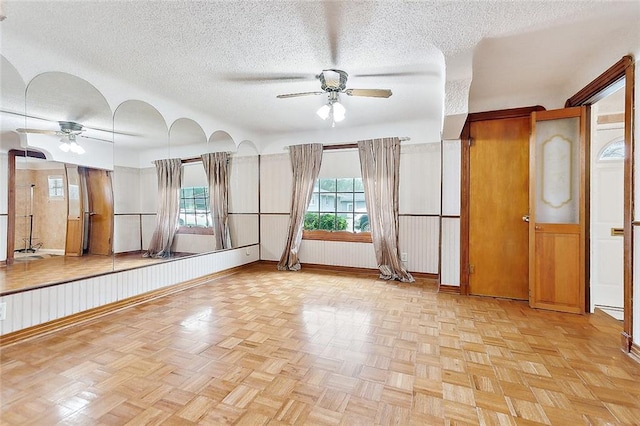 workout room with a textured ceiling, light parquet floors, and ceiling fan