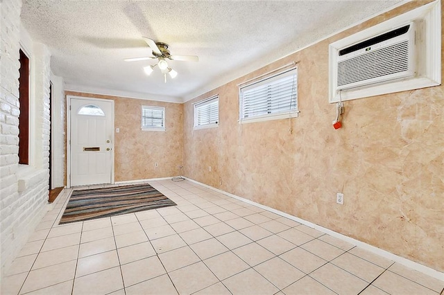 tiled foyer entrance with ceiling fan, an AC wall unit, and a textured ceiling