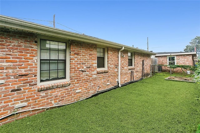 view of side of property with central air condition unit and a lawn