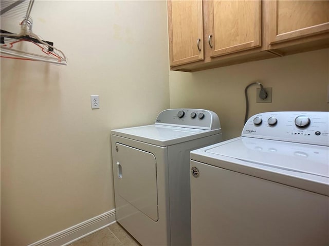 clothes washing area with washer and dryer, cabinets, and light tile patterned floors