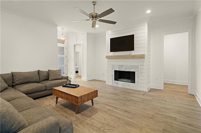 living room featuring a fireplace, light hardwood / wood-style floors, ceiling fan, and ornamental molding