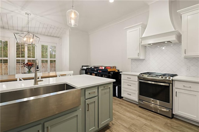 kitchen with white cabinetry, stainless steel gas range oven, light hardwood / wood-style floors, pendant lighting, and custom exhaust hood