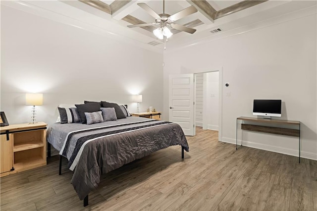 bedroom featuring coffered ceiling, crown molding, hardwood / wood-style flooring, ceiling fan, and beamed ceiling