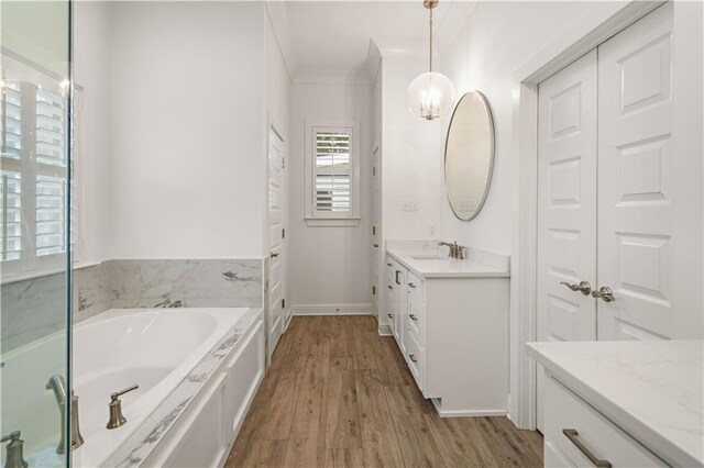 bathroom featuring a tub to relax in, vanity, ornamental molding, and hardwood / wood-style flooring