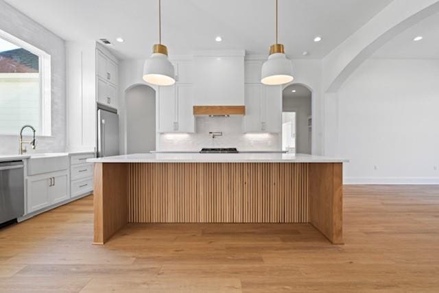 kitchen featuring white cabinets, a kitchen island, and pendant lighting