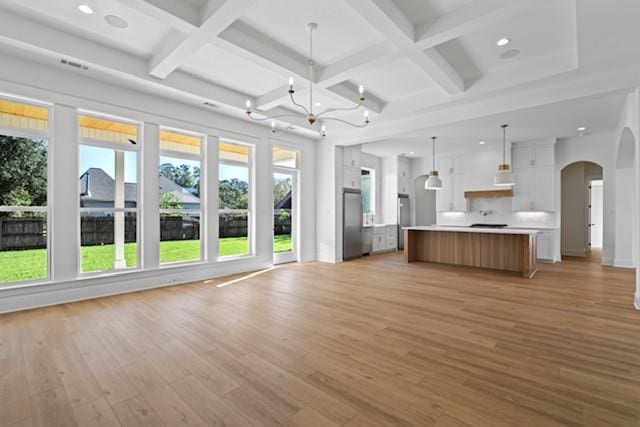 unfurnished living room featuring light hardwood / wood-style floors, beam ceiling, and coffered ceiling