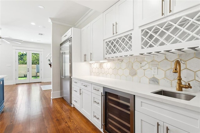 kitchen with white cabinetry, sink, wine cooler, stainless steel built in refrigerator, and decorative backsplash