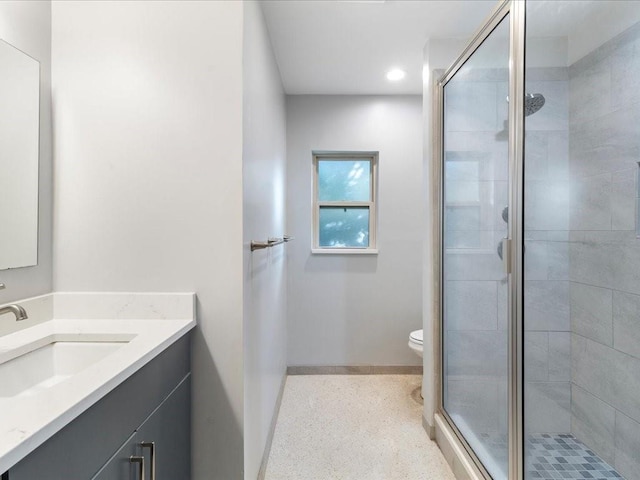 bathroom featuring vanity, toilet, and a shower with door