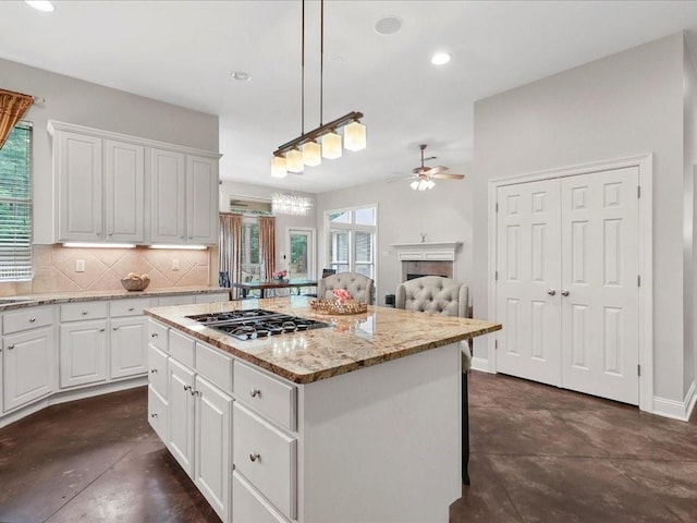 kitchen with white cabinets, a center island, decorative light fixtures, and plenty of natural light