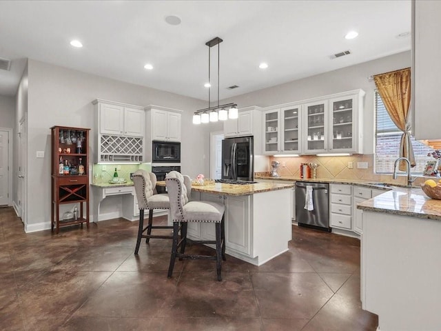 kitchen featuring a center island, black appliances, hanging light fixtures, light stone countertops, and white cabinetry