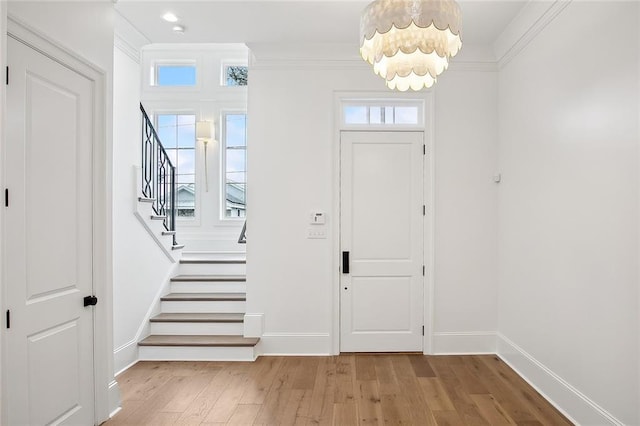 entryway with ornamental molding, light wood-type flooring, and a healthy amount of sunlight