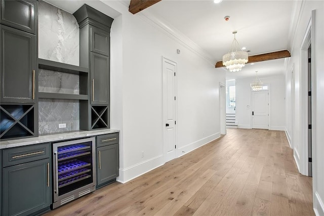 bar featuring tasteful backsplash, ornamental molding, beverage cooler, pendant lighting, and light hardwood / wood-style floors