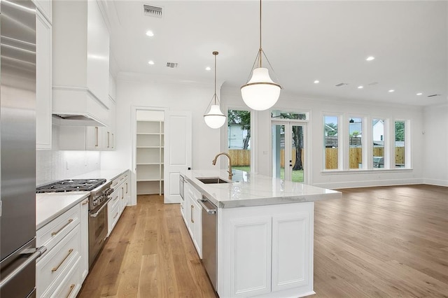 kitchen with pendant lighting, white cabinetry, high end appliances, and sink