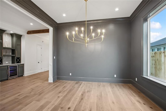 unfurnished dining area featuring light wood-type flooring, ornamental molding, beverage cooler, and a chandelier