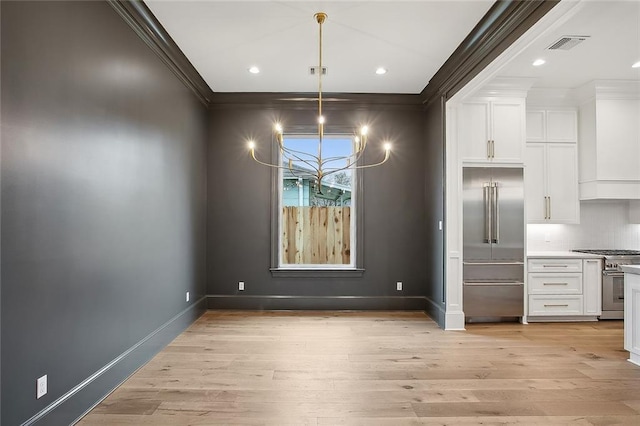 unfurnished dining area featuring light hardwood / wood-style flooring, a chandelier, and ornamental molding