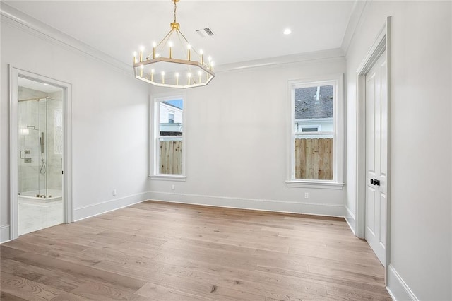 empty room featuring light hardwood / wood-style flooring, ornamental molding, and an inviting chandelier