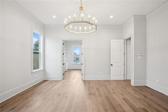 unfurnished dining area featuring crown molding, light hardwood / wood-style floors, and an inviting chandelier