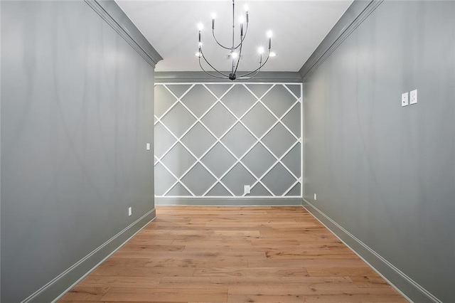 unfurnished dining area featuring a chandelier, ornamental molding, and light wood-type flooring