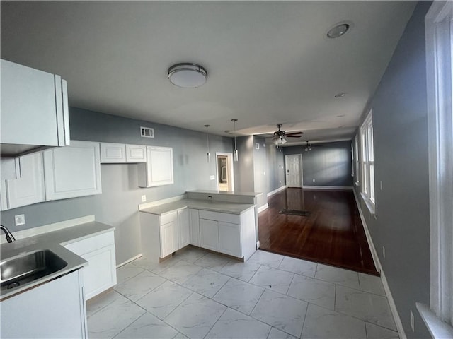 kitchen featuring kitchen peninsula, light wood-type flooring, ceiling fan, sink, and white cabinetry