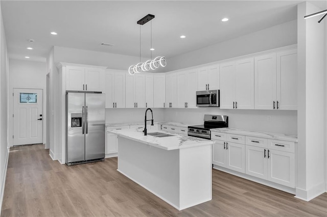 kitchen with pendant lighting, sink, light wood-type flooring, white cabinetry, and stainless steel appliances