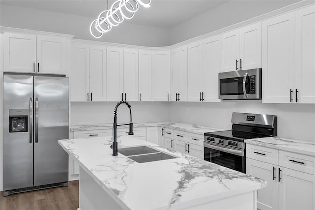 kitchen with a kitchen island with sink, sink, decorative light fixtures, dark hardwood / wood-style flooring, and stainless steel appliances