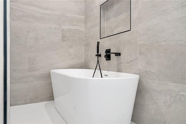 bathroom with a tub to relax in and tile walls