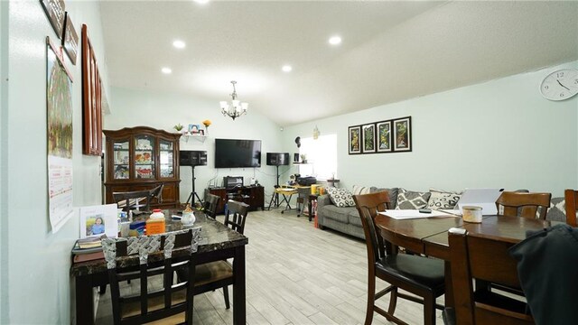 dining room featuring light hardwood / wood-style floors, lofted ceiling, and a notable chandelier