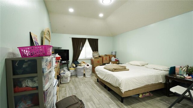 bedroom with wood-type flooring and vaulted ceiling