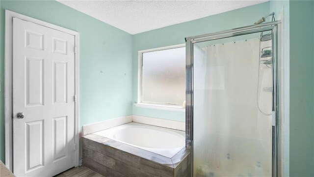 bathroom featuring a textured ceiling and independent shower and bath