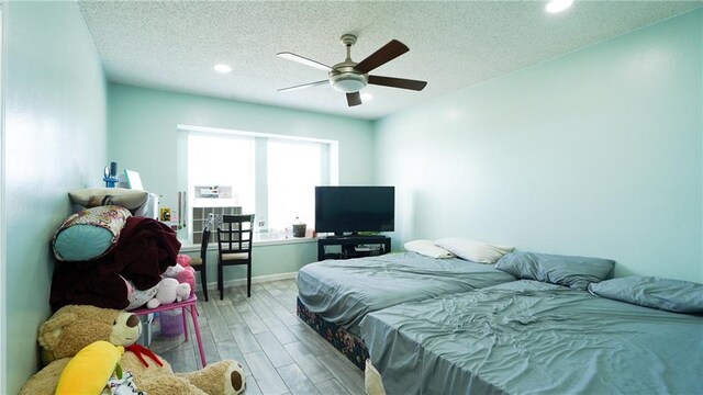 bedroom with a textured ceiling, hardwood / wood-style flooring, and ceiling fan