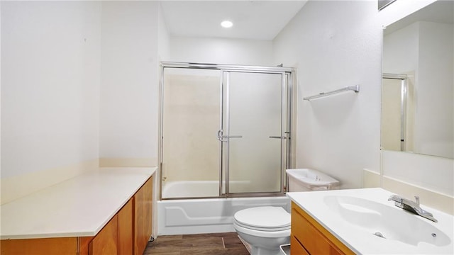 full bathroom with hardwood / wood-style floors, vanity, toilet, and combined bath / shower with glass door