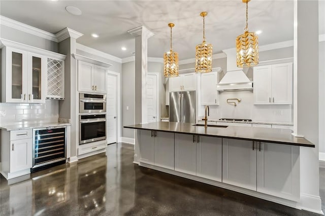 kitchen featuring wine cooler, appliances with stainless steel finishes, premium range hood, sink, and white cabinetry